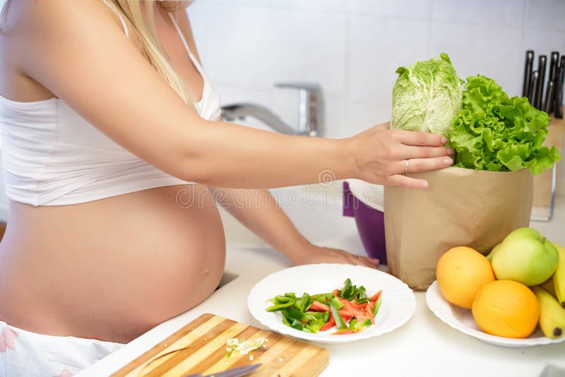 Schwangere Frau an der Küche, die oben Salat, Abschluss zubereitet lizenzfreie stockfotografie Schwangere Frau an der Küche, die oben Salat, Abschluss zubereitet lizenzfreie stockfotografie