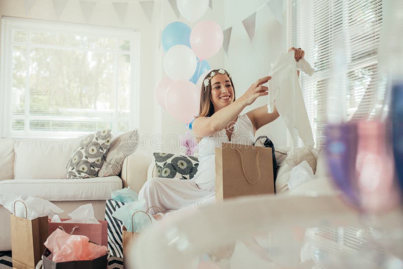 Schwangere Frau, die ein neues Geschenk nach Babyparty öffnet stockbild Schwangere Frau, die ein neues Geschenk nach Babyparty öffnet stockbild