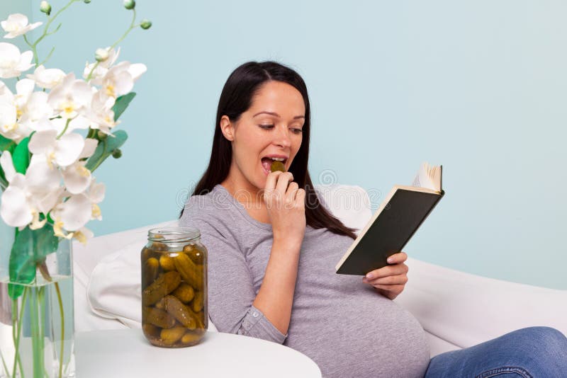 Schwangere Frau, die eine in Essig eingelegte Essiggurke isst. stockbilder Schwangere Frau, die eine in Essig eingelegte Essiggurke isst. stockbilder