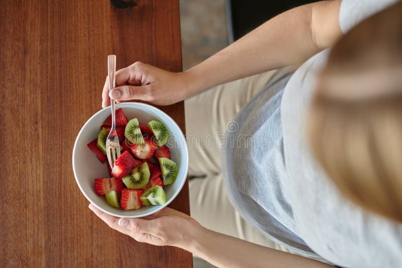 Schwangere Frau, die eine Schüssel Obstsalat isst lizenzfreie stockfotos Schwangere Frau, die eine Schüssel Obstsalat isst lizenzfreie stockfotos