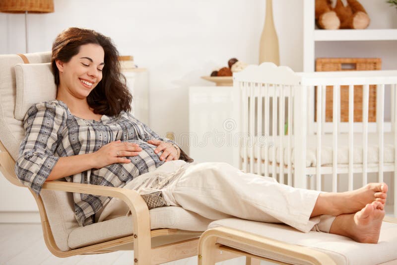 Schwangere Frau, die im Lehnsessel in der Kindertagesstätte stillsteht stockbilder Schwangere Frau, die im Lehnsessel in der Kindertagesstätte stillsteht stockbilder