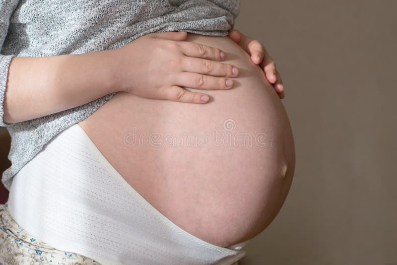 Schwangere Frau im orthopädischen Stützgurt, Schwangerschaftsverband, ihren Bauch halten lizenzfreies stockbild Schwangere Frau im orthopädischen Stützgurt, Schwangerschaftsverband, ihren Bauch halten lizenzfreies stockbild