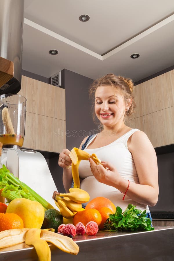 Schwangere Frau macht einen Frucht Smoothie für und ihr Kind in der Küche lizenzfreie stockbilder Schwangere Frau macht einen Frucht Smoothie für und ihr Kind in der Küche lizenzfreie stockbilder