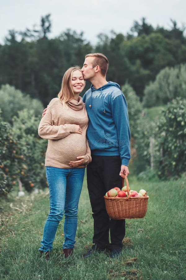 Schwangere junge blonde kaukasische Frau mit Ehemann auf Apfelbauernhof stockfotografie Schwangere junge blonde kaukasische Frau mit Ehemann auf Apfelbauernhof stockfotografie