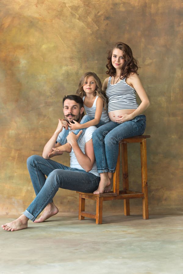 Schwangere Mutter mit jugendlich Tochter und Ehemann Familienstudioporträt über braunem Hintergrund lizenzfreies stockfoto Schwangere Mutter mit jugendlich Tochter und Ehemann Familienstudioporträt über braunem Hintergrund lizenzfreies stockfoto
