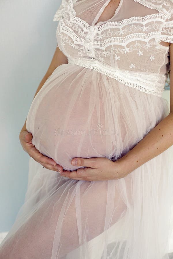 Schwangeres Mädchen in den weißen transparenten Kleiderständen lizenzfreie stockfotografie Schwangeres Mädchen in den weißen transparenten Kleiderständen lizenzfreie stockfotografie