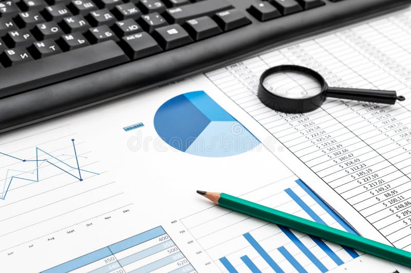 Schwarze Computertastatur mit Stift auf Dokumente mit Finanzdaten.