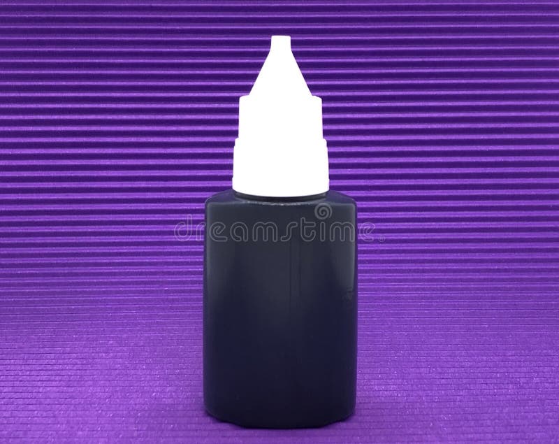 Schwarze Farbe füllte ab. Schwarze Farbe innerhalb der Plastikflasche auf dem lila strukturierten Hintergrund.