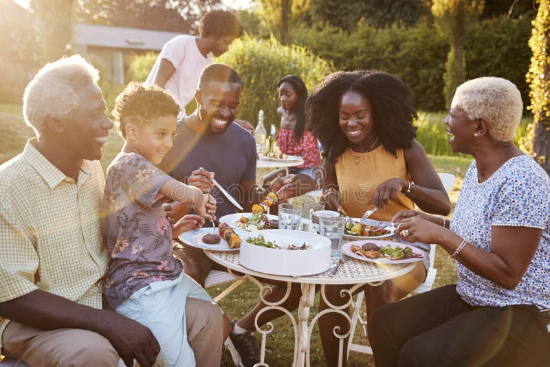 Schwarze multi Generationsfamilie, die an einem Tisch im Garten isst lizenzfreies stockfoto Schwarze multi Generationsfamilie, die an einem Tisch im Garten isst lizenzfreies stockfoto