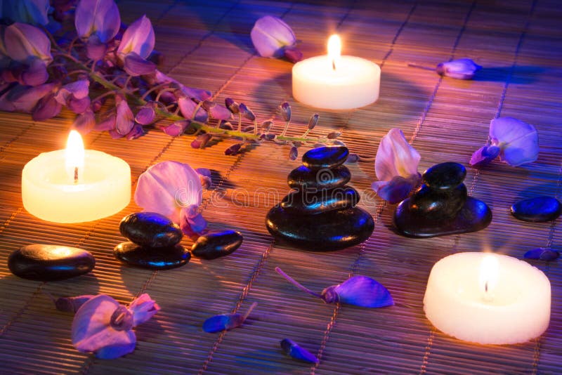 Schwarze Steine, violette Blumen und Kerzen auf Bambus stockfoto Schwarze Steine, violette Blumen und Kerzen auf Bambus stockfoto