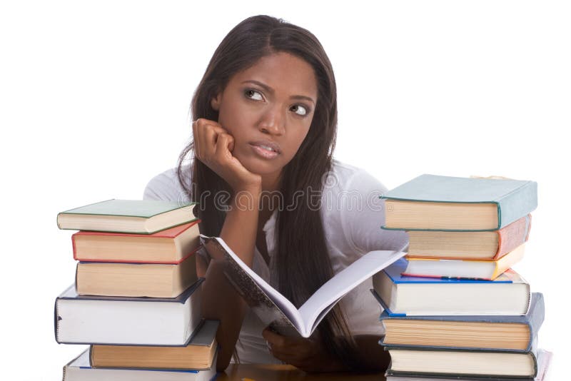 High school or college ethnic African-American female student sitting by the desk with lot of books in class or library and doing homework. High school or college ethnic African-American female student sitting by the desk with lot of books in class or library and doing homework