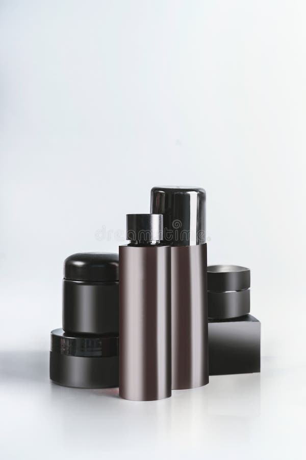 Schwarze und braune kosmetische Produktgläser und -flaschen mit einbrennendem Spott oben, stehend auf Leuchtpult am Wandhintergru