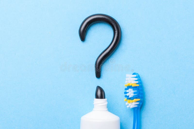 Schwarze Zahnpasta von der Holzkohle für weiße Zähne Zahnpasta in Form von Fragezeichen, Rohr und Zahnbürste auf Blau lizenzfreie stockfotografie