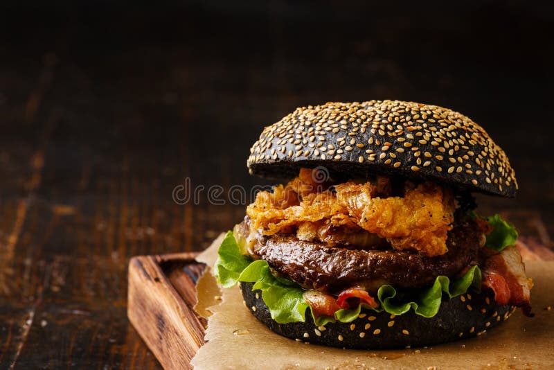 Schwarzer Burger mit Fleisch- und Zwiebelringen brät stockbilder Schwarzer Burger mit Fleisch- und Zwiebelringen brät stockbilder
