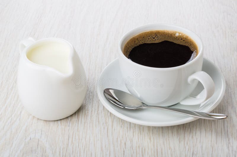Schwarzer Kaffee in der Schale, Löffel auf Untertasse, Krug Milch stockfotos
