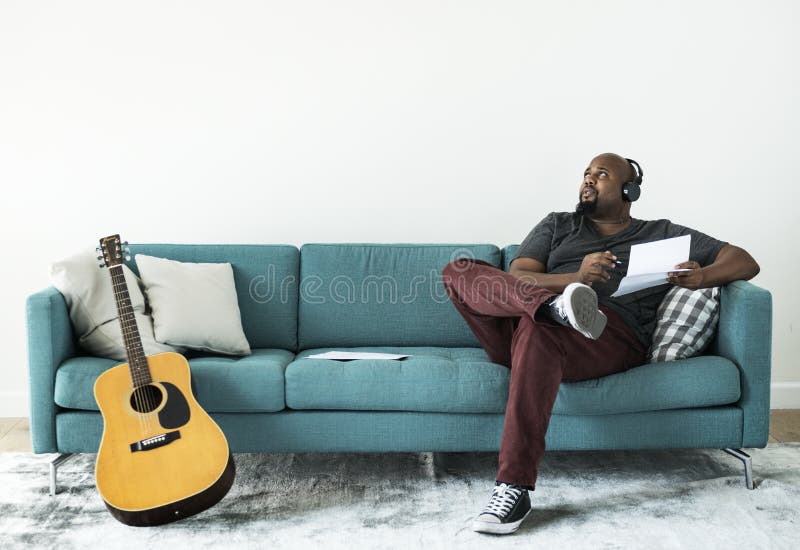 Schwarzer Mann, der neues Lied auf einer Couch komponiert
