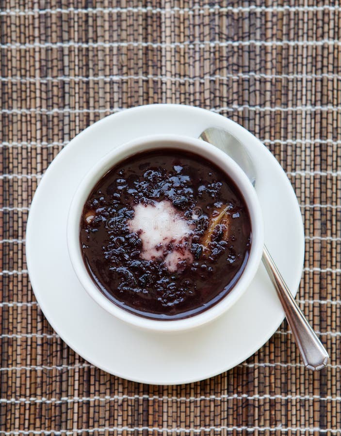 Schwarzer Pudding des klebrigen Reises mit Kokosmilch im hölzernen Hintergrund der weißen Schüssel lizenzfreie stockfotografie Schwarzer Pudding des klebrigen Reises mit Kokosmilch im hölzernen Hintergrund der weißen Schüssel lizenzfreie stockfotografie