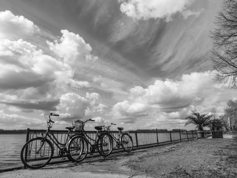 Artistic black and white photo of 3 parked bicycles and a vast cloudy sky as background. Artistic black and white photo of 3 parked bicycles and a vast cloudy sky as background