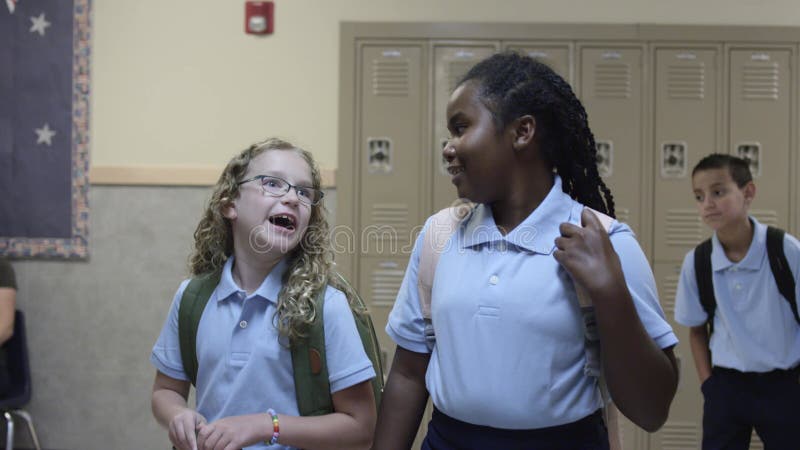 Schwarzweiss-Mädchen reden und lachen in der Schulhalle auf dem Weg, um zu klassifizieren