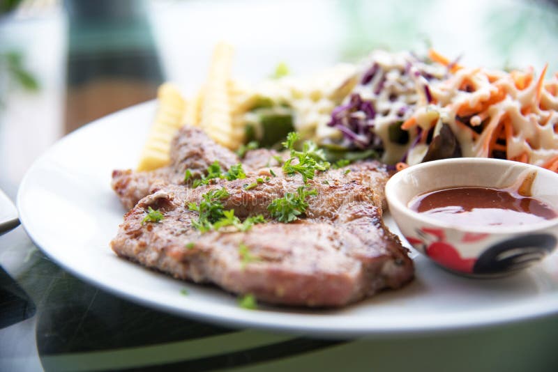 Schweinekotelettsteak mit Salat und Soße sauce im Teller Lebensmittel und Veg lizenzfreie stockfotos Schweinekotelettsteak mit Salat und Soße sauce im Teller Lebensmittel und Veg lizenzfreie stockfotos