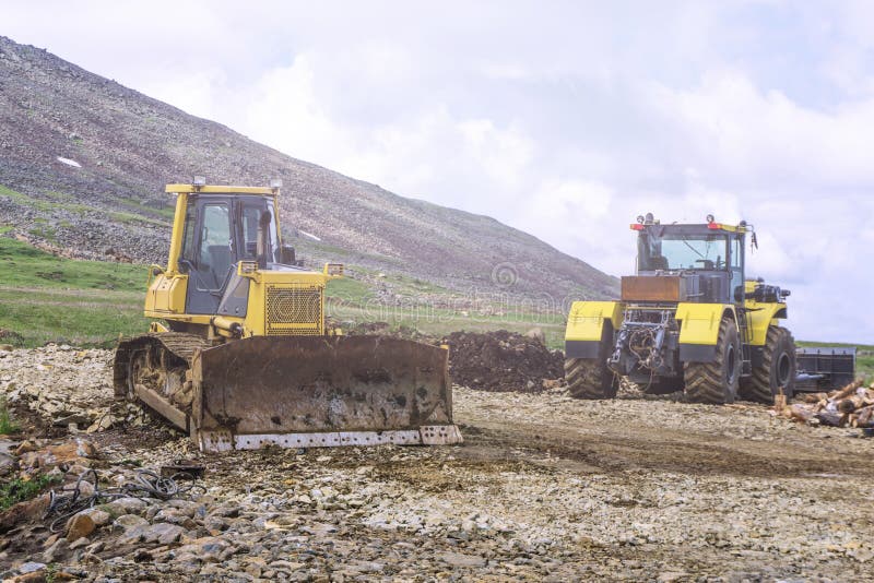 Heavy machinery two bulldozers on the construction of roads in the mountains. Heavy machinery two bulldozers on the construction of roads in the mountains