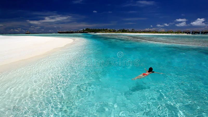 Schwimmen der jungen Frau in der tropischen Lagune