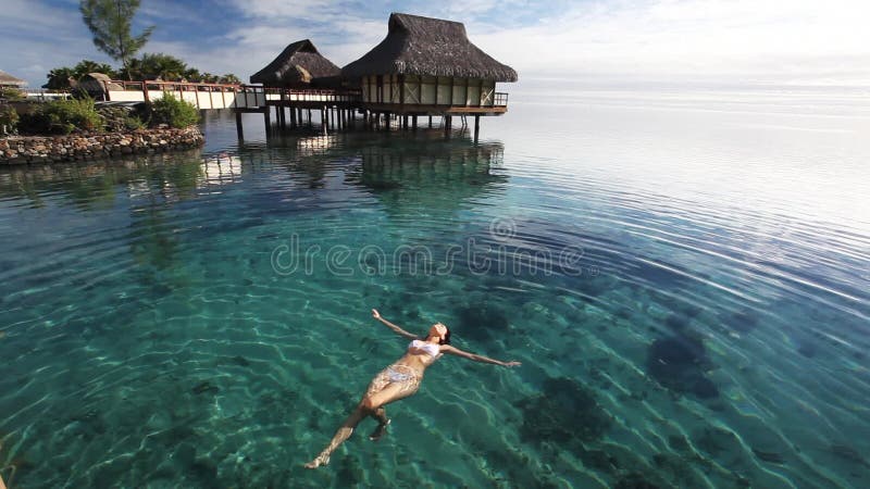 Schwimmen der jungen Frau in einer korallenroten Lagune