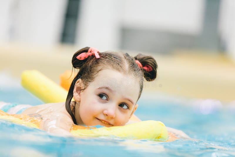 Schwimmen des kleinen Mädchens mit einer gelben Nudel in einem Pool stockfotografie Schwimmen des kleinen Mädchens mit einer gelben Nudel in einem Pool stockfotografie