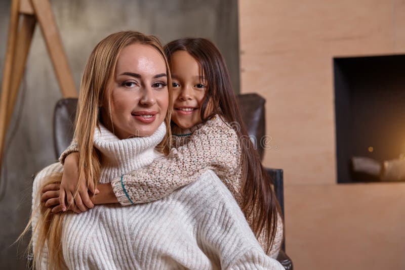 Schöne Mutterfrau in der weißen Strickjacke umarmt ihre kleine Tochter Nette spielerische Stimmung und Liebe innerhalb der Famili lizenzfreie stockfotografie Schöne Mutterfrau in der weißen Strickjacke umarmt ihre kleine Tochter Nette spielerische Stimmung und Liebe innerhalb der Famili lizenzfreie stockfotografie