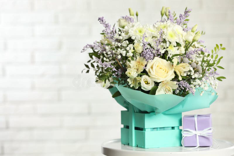 Schöner Blumenstrauß von Blumen und von Geschenkbox auf Tabelle gegen hellen Hintergrund stockfoto