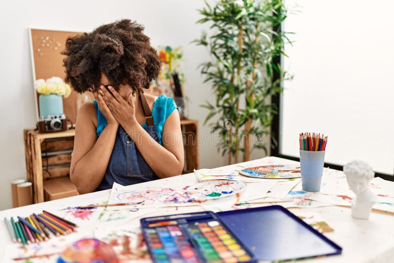 Beautiful african american woman with afro hair painting at art studio with sad expression covering face with hands while crying. depression concept. Beautiful african american woman with afro hair painting at art studio with sad expression covering face with hands while crying. depression concept