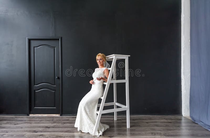 Schöne blonde Braut der jungen Frau auf der hölzernen Treppe im Innenraum im Studio stockfoto Schöne blonde Braut der jungen Frau auf der hölzernen Treppe im Innenraum im Studio stockfoto