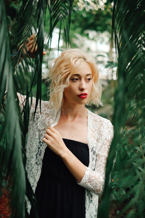 Schöne Blondine, die im tropischen botanischen Garten aufwerfen lizenzfreie stockfotografie Schöne Blondine, die im tropischen botanischen Garten aufwerfen lizenzfreie stockfotografie