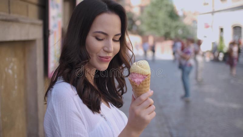 Schöne brunette Frau, die köstliche und süße Eiscreme isst