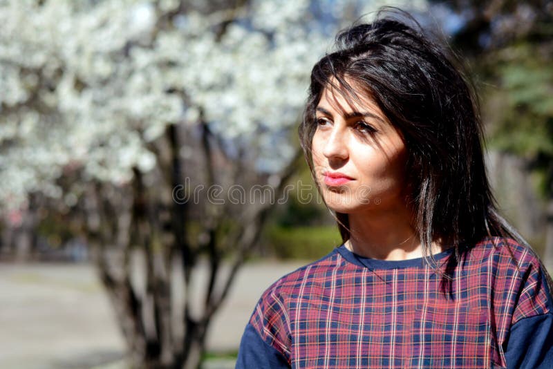 Schöne denkende Brunettefrau in einem Frühlingsgarten lizenzfreies stockbild Schöne denkende Brunettefrau in einem Frühlingsgarten lizenzfreies stockbild
