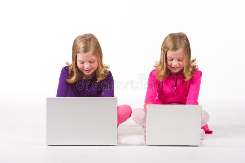Schöne Doppelmädchen, die an Computern arbeiten