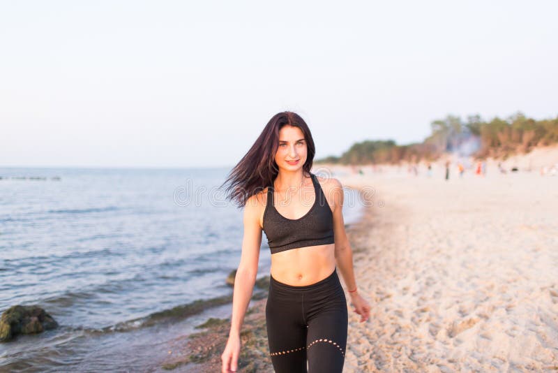 Schöne Fitness-Sportlerin, die nach dem Training am Strandsommerabend bei sonniger Sonneneinstrahlung im Außenportrait lizenzfreies stockfoto Schöne Fitness-Sportlerin, die nach dem Training am Strandsommerabend bei sonniger Sonneneinstrahlung im Außenportrait lizenzfreies stockfoto