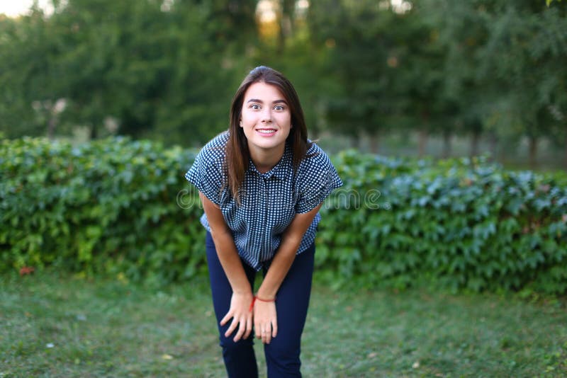 Schöne Frau, die in camera schaut und herum an im Park täuscht lizenzfreie stockfotografie