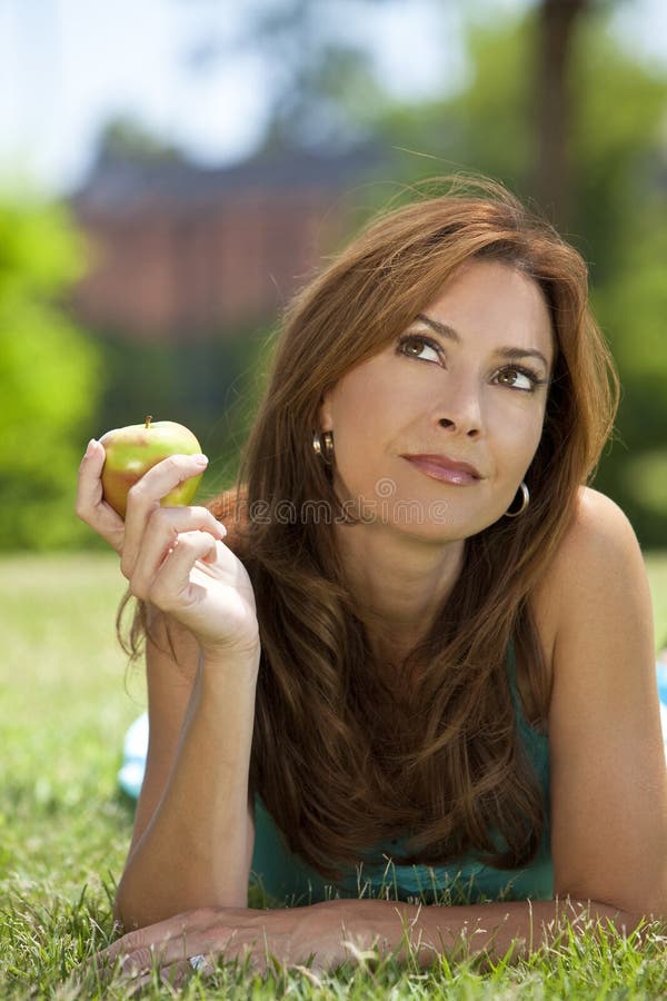 Schöne Frau, die einen Apple u. ein Denken isst lizenzfreie stockfotos Schöne Frau, die einen Apple u. ein Denken isst lizenzfreie stockfotos