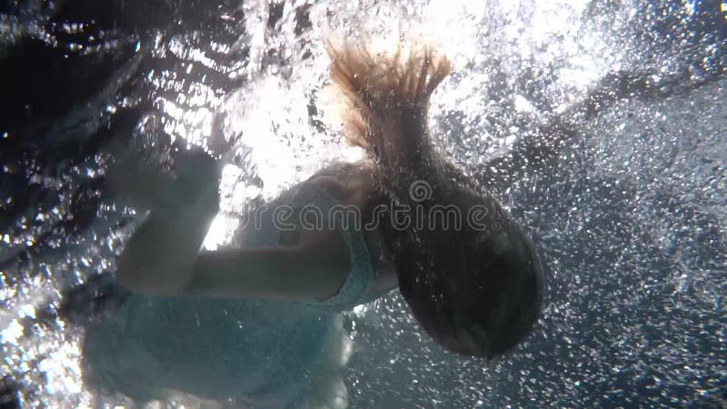 Schöne Frau mit langen roten Haaren schwimmen unter Wasser in Kleid