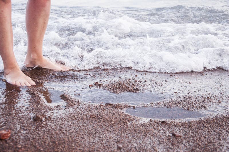 Schöne Frauenfahrwerkbeine auf dem Strand am Sonnenuntergang lizenzfreies stockfoto Schöne Frauenfahrwerkbeine auf dem Strand am Sonnenuntergang lizenzfreies stockfoto