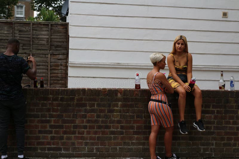 Schöne glückliche Damen Notting- Hillkarnevals, die auf Handlauf sitzen und Partei genießen stockfotos Schöne glückliche Damen Notting- Hillkarnevals, die auf Handlauf sitzen und Partei genießen stockfotos