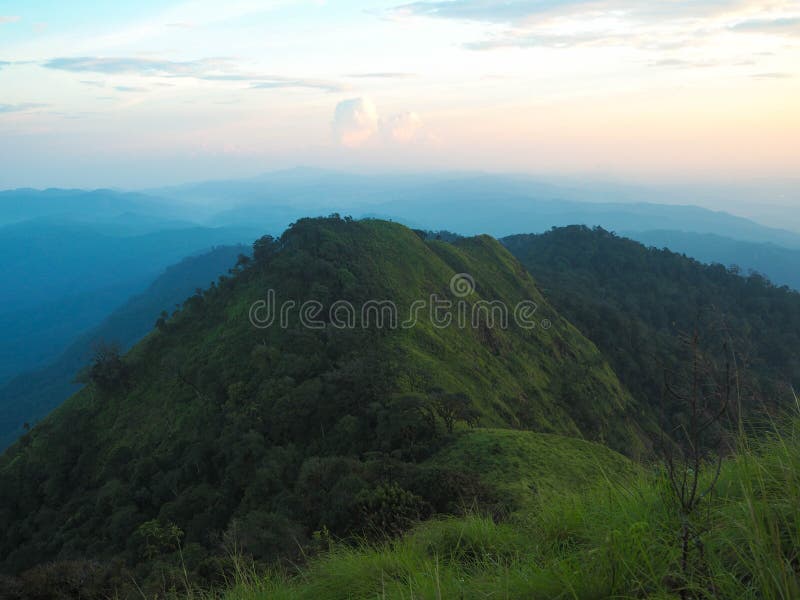 Schöne Grünlandschaft durch Berg und Sonnenunterganghimmel mit Wiese stockfoto Schöne Grünlandschaft durch Berg und Sonnenunterganghimmel mit Wiese stockfoto