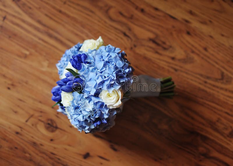 Beautiful wedding flowers bouquet and wedding rings on the wooden dark background, focus on rings. Beautiful wedding flowers bouquet and wedding rings on the wooden dark background, focus on rings