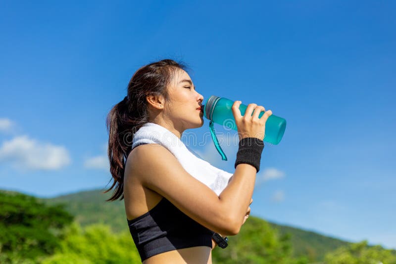 Schöne junge Asiatin, die morgens an einer Laufbahn, eine Pause machend, um Wasser zu trinken trainiert stockbilder Schöne junge Asiatin, die morgens an einer Laufbahn, eine Pause machend, um Wasser zu trinken trainiert stockbilder