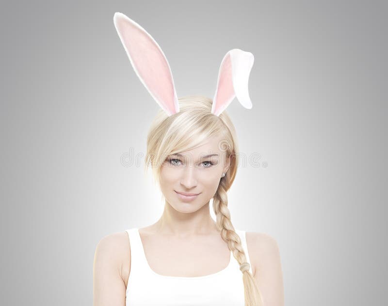 Beautiful young blond woman as easter bunny with rabbit ears on grey background. Beautiful young blond woman as easter bunny with rabbit ears on grey background