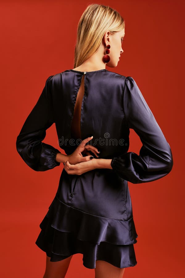 Schöne junge Blondine im eleganten schwarzen Cocktailkleid mit Ausschnitt werfen für Kamera auf lizenzfreies stockbild Schöne junge Blondine im eleganten schwarzen Cocktailkleid mit Ausschnitt werfen für Kamera auf lizenzfreies stockbild