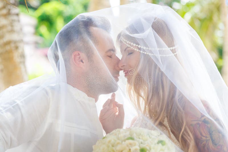 Schöne junge Braut im Schleier, mit Hochzeitsblumenstrauß von Weiß stockfotografie Schöne junge Braut im Schleier, mit Hochzeitsblumenstrauß von Weiß stockfotografie