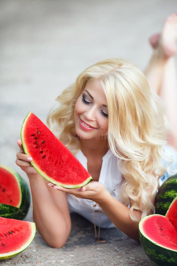 Schöne junge Frau, die eine Scheibe der reifen Wassermelone hält lizenzfreie stockbilder Schöne junge Frau, die eine Scheibe der reifen Wassermelone hält lizenzfreie stockbilder
