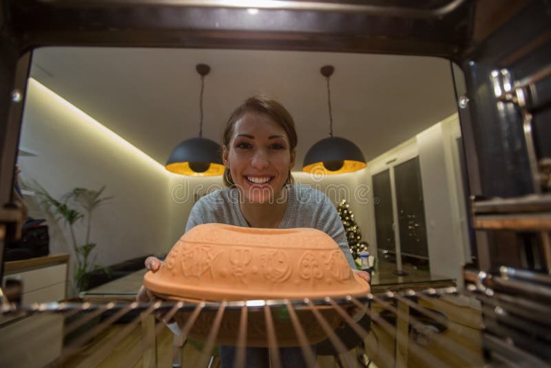 Schöne junge Frau, die etwas in den Ofen einsetzt zu kochen stockfotos Schöne junge Frau, die etwas in den Ofen einsetzt zu kochen stockfotos